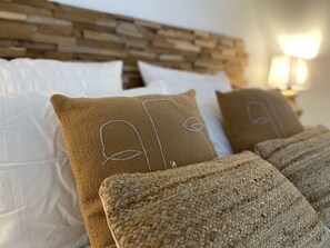 A bed with white and beige pillows, a woven blanket, and a wooden headboard. - Le Domaine d'Angerville (Angerville)