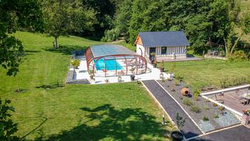 Ein Haus mit Pool, überdachter Terrasse und Garten.