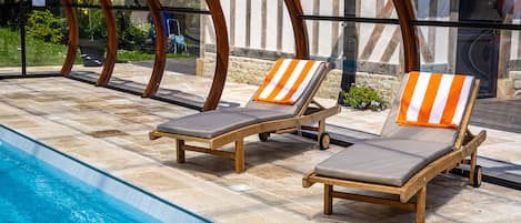 A poolside area with lounge chairs and a glass-enclosed structure.
