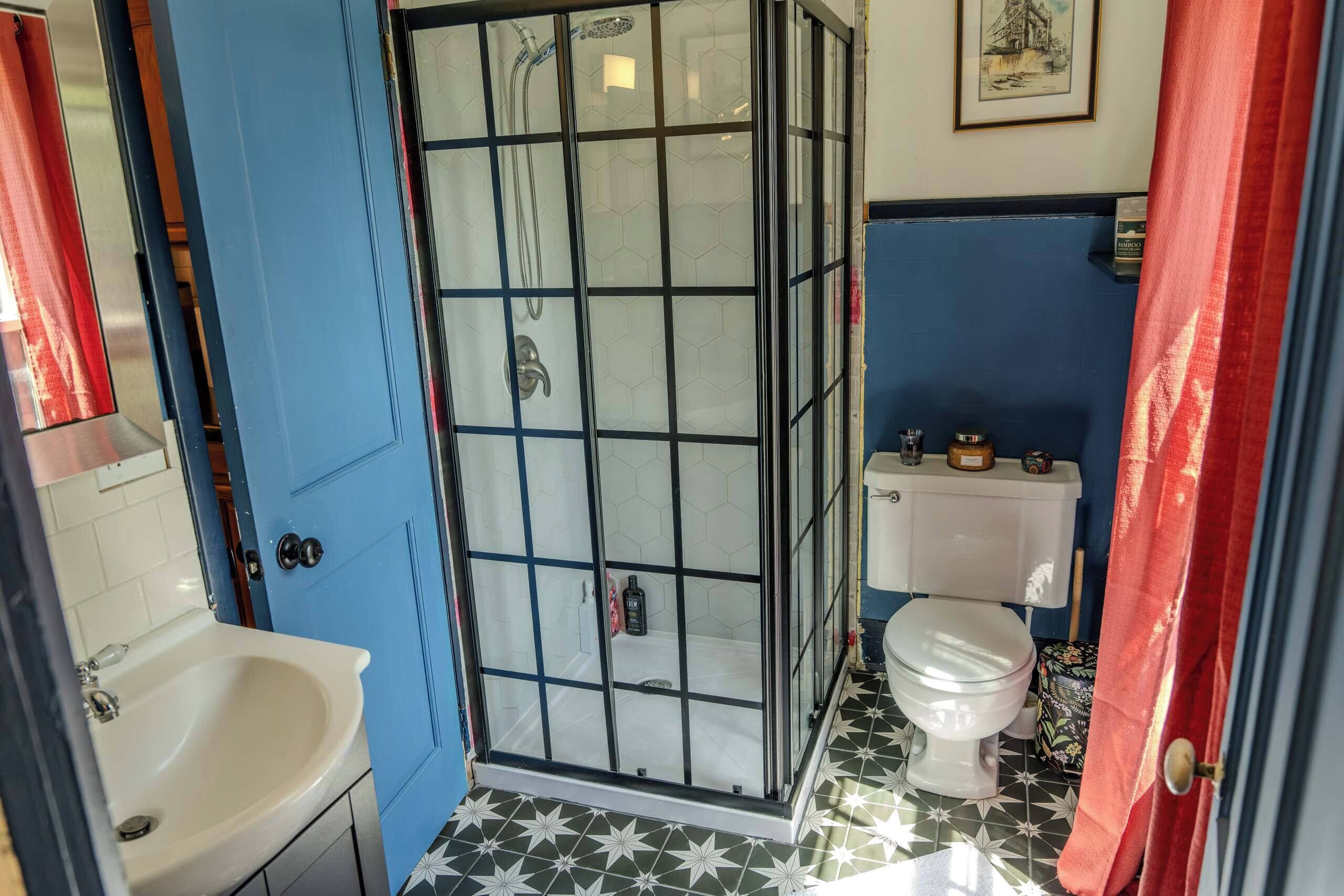 A bathroom with a shower enclosure, a toilet, and a sink.