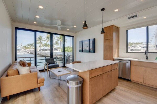 Una cocina moderna con una isla grande, armarios de madera y vistas al puerto deportivo.