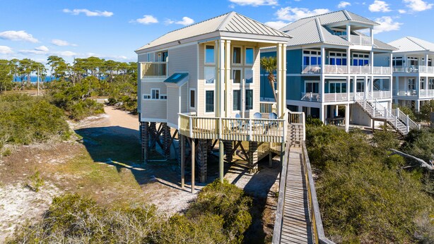 A beachfront house with multiple levels, a wooden deck, and a view of the ocean. - Rising Sun: Cozy 2 BR Beachfront Home on East End- Sleeps 8, Pet Friendly! (St. George Island)