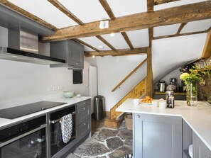 A modern kitchen with a stone floor, wooden beams, and a variety of appliances. - 2 bedroom accommodation in Ludlow (Ludlow)