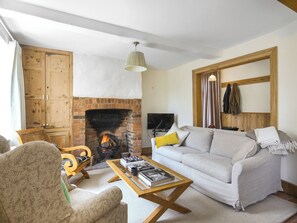 A cozy living room with a fireplace, a sofa, a coffee table with books, and a television.