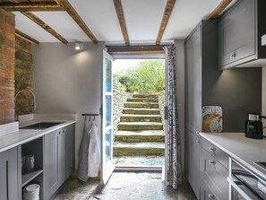Une cuisine étroite avec un escalier en pierre menant à un espace extérieur.