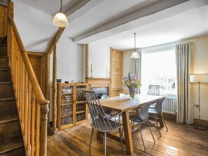 A wooden dining table with chairs, a glass cabinet with wine glasses, and a vase with flowers. - 2 bedroom accommodation in Ludlow (Ludlow)