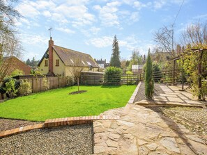 A well-maintained garden with a stone pathway, a wooden fence, and a house with a sloped roof. - 2 bedroom accommodation in Ludlow (Ludlow)