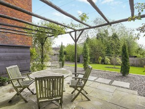 An outdoor patio with a wooden table and four chairs, surrounded by a brick wall and a wooden pergola. - 2 bedroom accommodation in Ludlow (Ludlow)