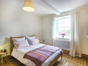 A bedroom with a wooden bed, white walls, a window with curtains, and a radiator. - 2 bedroom accommodation in Ludlow (Ludlow)