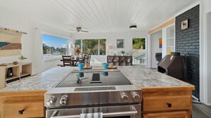 A modern kitchen with a large island, built-in oven, and a stone fireplace. - Treasure Hideaway-Manzanita Or., Ocean View,Fenced Yard, Arcade games, Dog Ok (Nehalem)