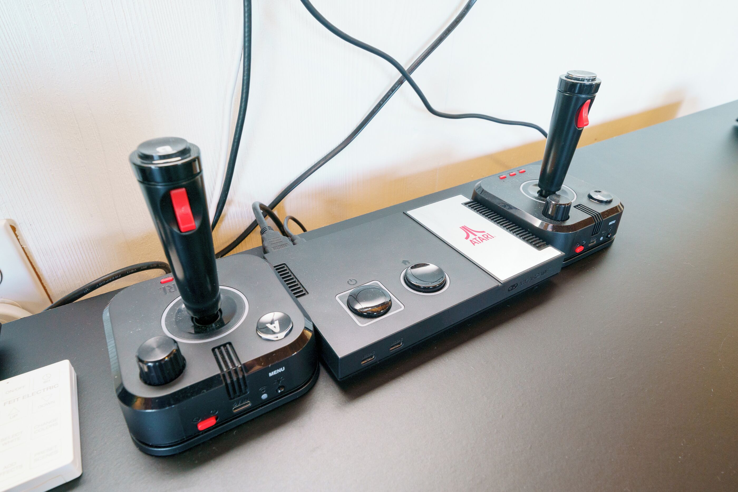 Two gaming joysticks on a table with a white and black design, connected by wires.