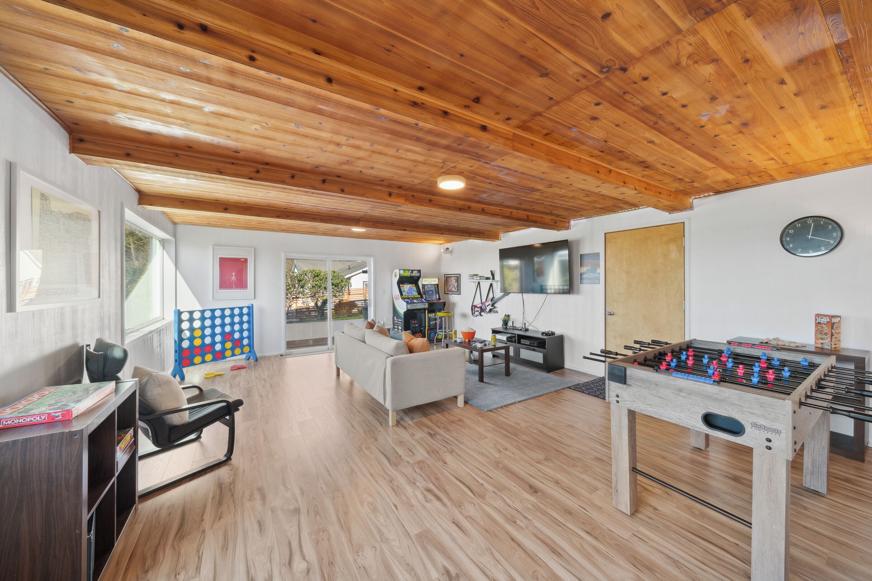 Un salón amplio con techo de madera, mesa de fútbol de mesa, sofá y mesa de centro.