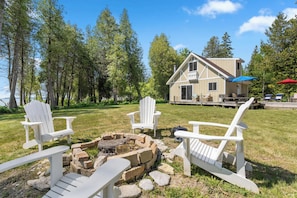 A house with a deck, a fire pit, and three Adirondack chairs. - Waterfront Lake Michigan Tranquility Bay Getaway (Sister Bay)