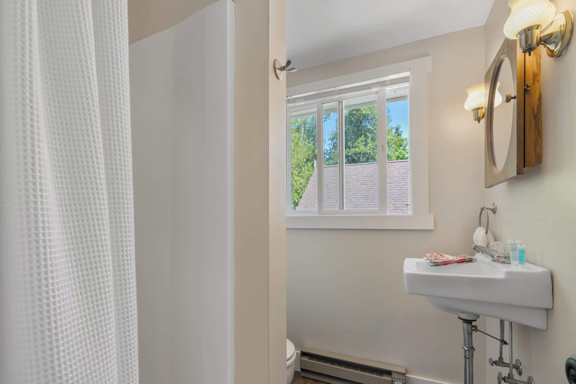 A bathroom with a window, a sink, and a shower curtain.