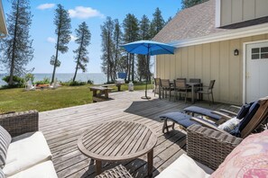 A deck with outdoor furniture, a table, and chairs, overlooking a body of water. - Waterfront Lake Michigan Tranquility Bay Getaway (Sister Bay)