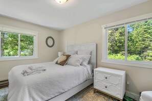 A bedroom with a bed, bedside table, and two windows with a view of trees. - Waterfront Lake Michigan Tranquility Bay Getaway (Sister Bay)