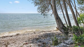 A rocky shoreline with trees and calm water. - Waterfront Lake Michigan Tranquility Bay Getaway (Sister Bay)