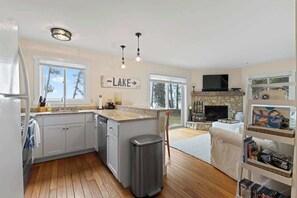 A kitchen with a stone fireplace, a TV, and a sign that says 'LAKE'. - Waterfront Lake Michigan Tranquility Bay Getaway (Sister Bay)