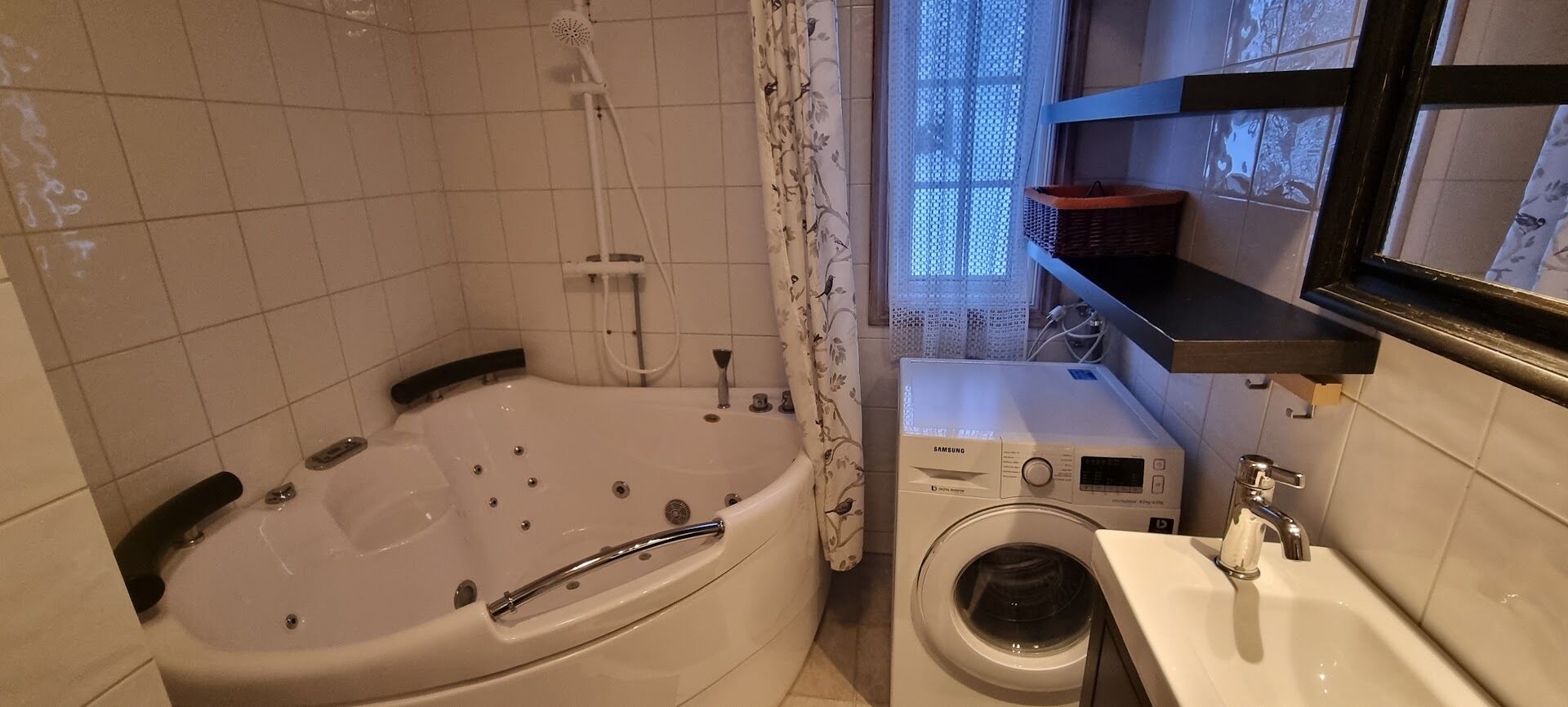 A bathroom with a bathtub, a washing machine, and a sink.