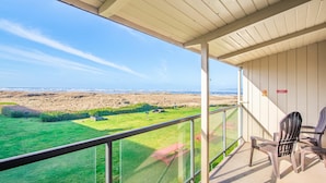 A balcony with a view of a grassy field and beach.