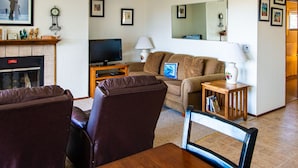 A living room with a fireplace, a television, a sofa, and a dining table.