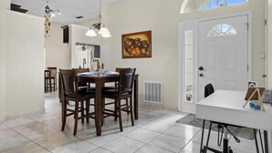 Un espace repas avec une table ronde et des chaises, un tableau blanc et un tableau accroché au mur.