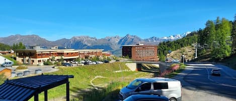 Une vue d’une route, avec un bâtiment et des montagnes en arrière-plan.