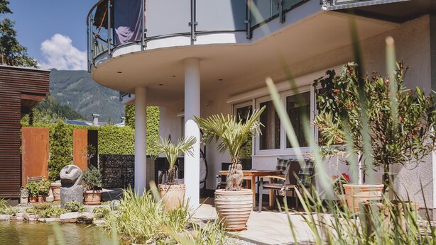 Ein modernes Haus mit Pool, Topfpflanzen und Gartenmöbeln.