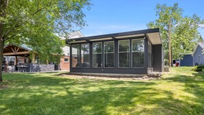 Une maison moderne dotée d’une grande extension à fenêtres, de fondations en pierre et d’une pelouse bien entretenue.