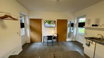 Una cocina compacta con una mesa, sillas, un televisor y una ventana.