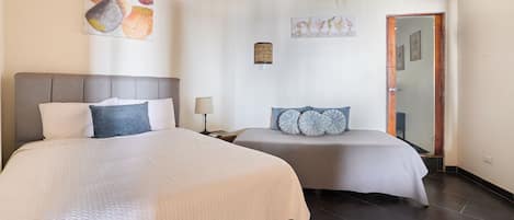 A hotel room with two beds, a wooden ceiling, and artwork on the walls.
