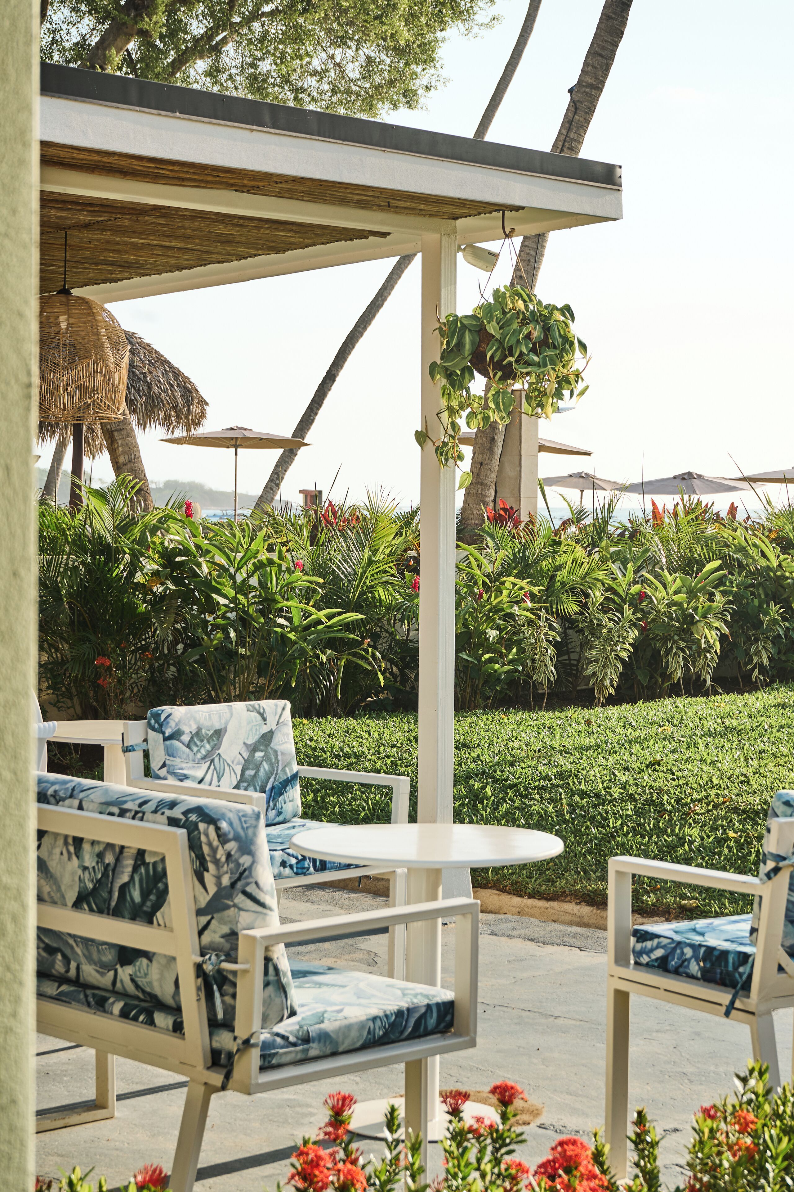 Outdoor seating with white and blue patterned furniture, a white table, and lush greenery in the background.