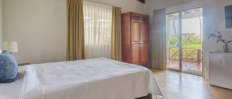 Un dormitorio con cama, armario de madera y vistas al exterior por un ventanal corredero.