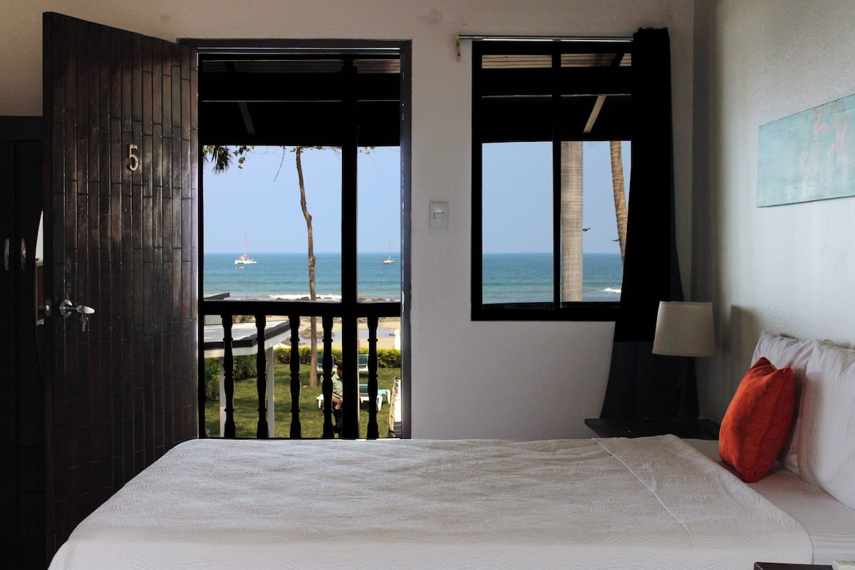 A bedroom with a large bed, a view of the sea, and a balcony.