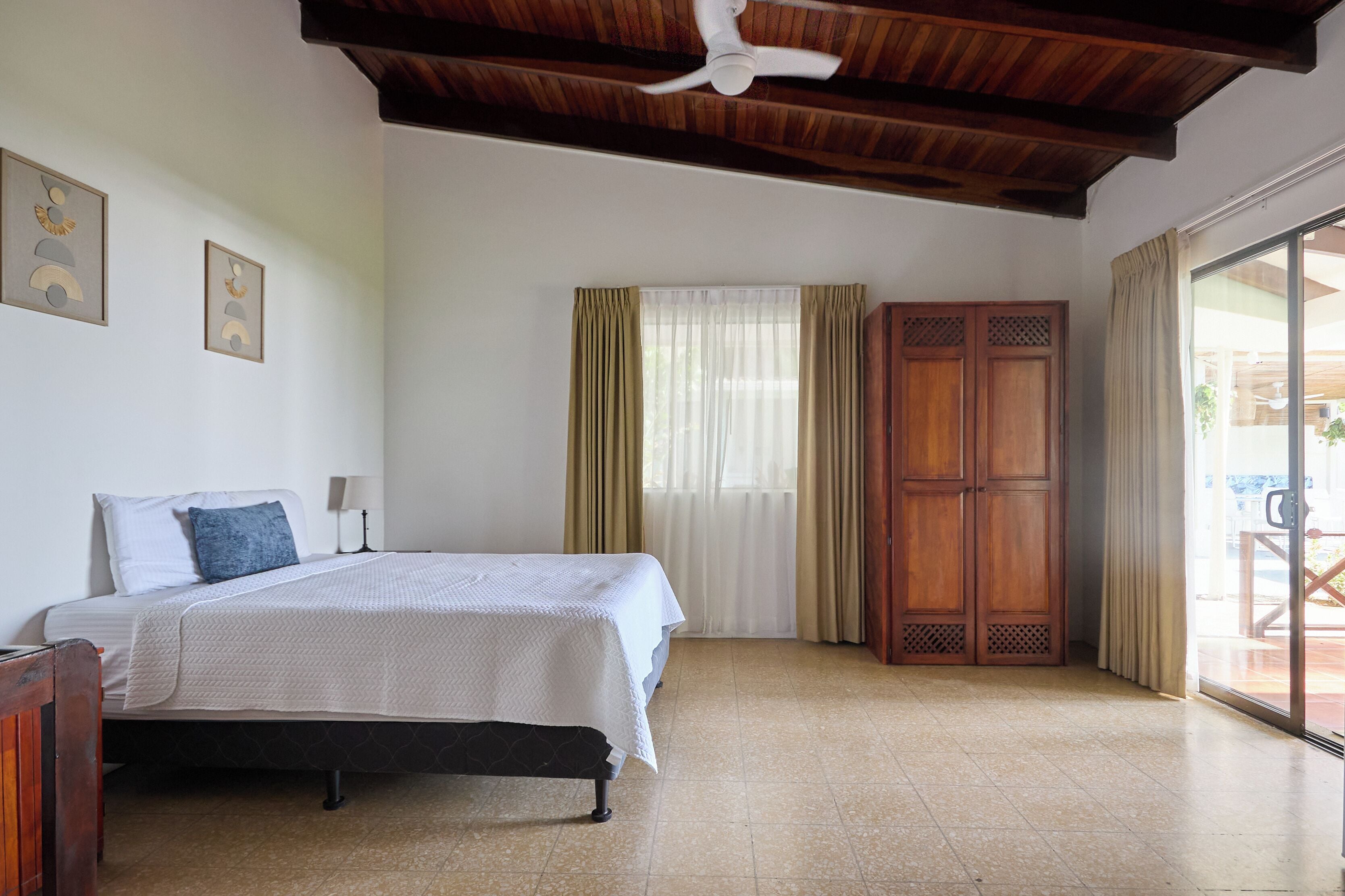 Un dormitorio con cama, armario de madera y ventilador de techo.