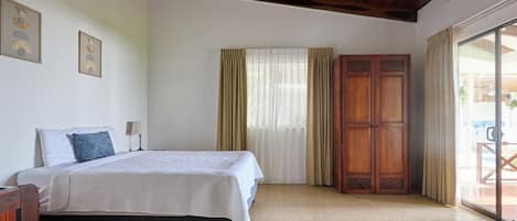 Une chambre à coucher avec un lit, une armoire en bois et un ventilateur de plafond.
