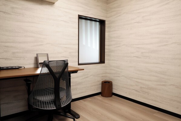 A small, modern office space with a wooden desk, a mesh office chair, a small trash can, and a window with blinds. - Kyomachiya Bettei Hanatei (Kyoto)