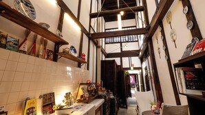 A narrow hallway with wooden beams and tiled walls, featuring shelves with various items and a counter with a display. - Kyomachiya Bettei Hanatei (Kyoto)