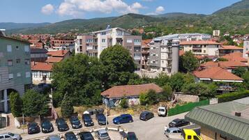 Un parking avec plusieurs voitures, un camion jaune et un bâtiment doté d’un toit végétalisé.