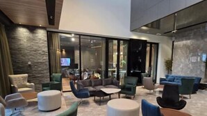 A modern lobby with a mix of seating options, including sofas and armchairs, and a large glass wall offering a view of the interior. - Vojvoda Putnik (Vranje)