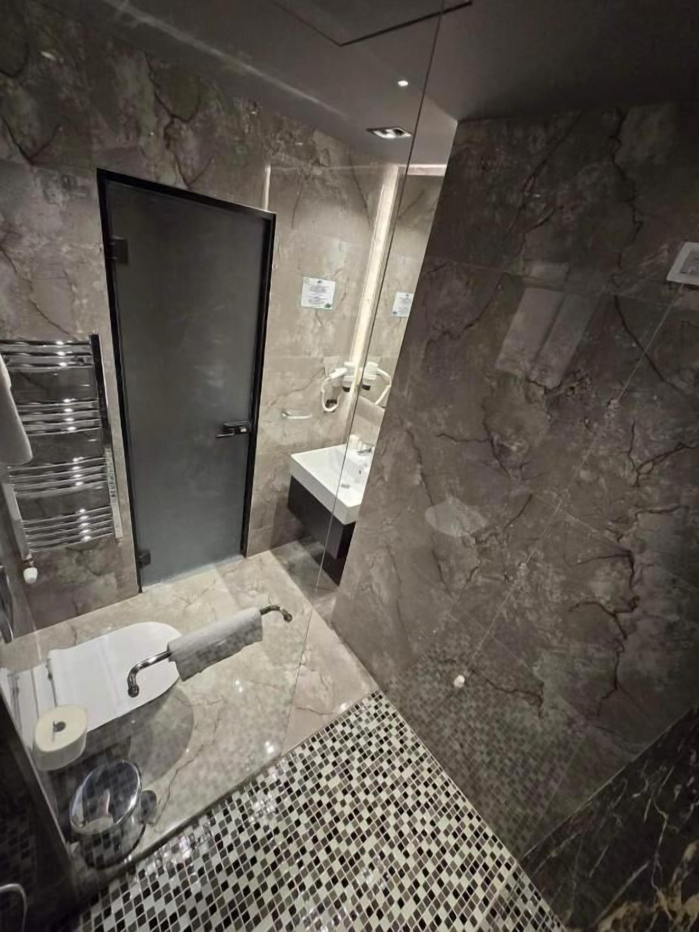 A bathroom with a marble sink, a toilet, and a shower area.