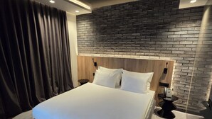 A modern hotel room with a large bed, a brick accent wall, and a minimalist design. - Vojvoda Putnik (Vranje)