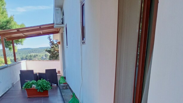 A balcony with wicker furniture, potted plants, and a view of the landscape. - Accogliente Camera con Grande Terrazzo. Animali Domestici Ammessi (Vieste)