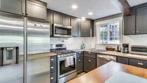 Una cocina moderna con electrodomésticos de acero inoxidable, encimeras de madera y un amplio ventanal que proporciona luz natural.