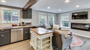 Una cocina moderna con armarios oscuros, una isla de madera y un televisor integrado.
