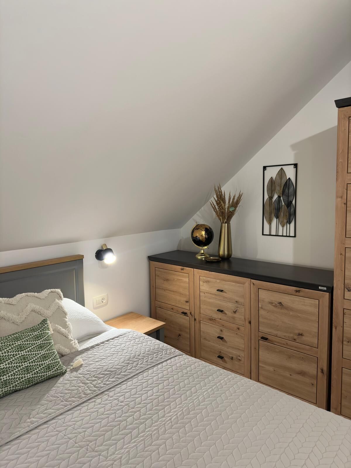 Un dormitorio con cama, cómoda de madera, un globo terráqueo y decoración en la pared.