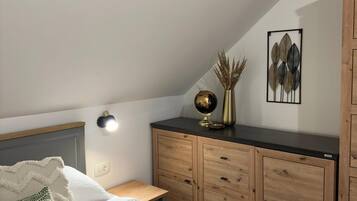 Un dormitorio con cama, cómoda de madera, un globo terráqueo y decoración en la pared.