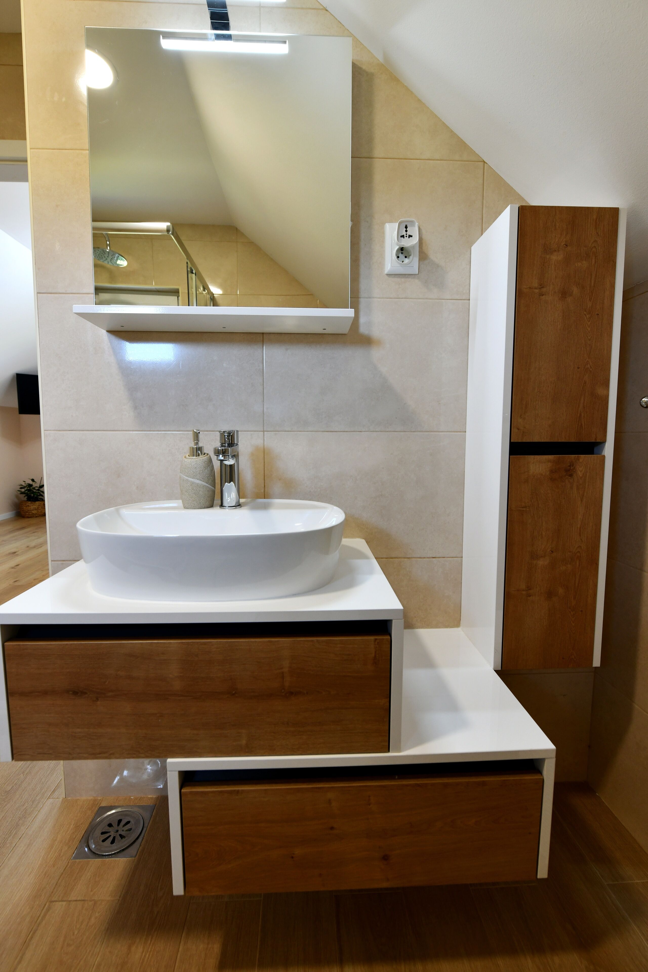Une salle de bain moderne avec un grand lavabo blanc, un meuble-lavabo en bois, un miroir et un placard en bois.
