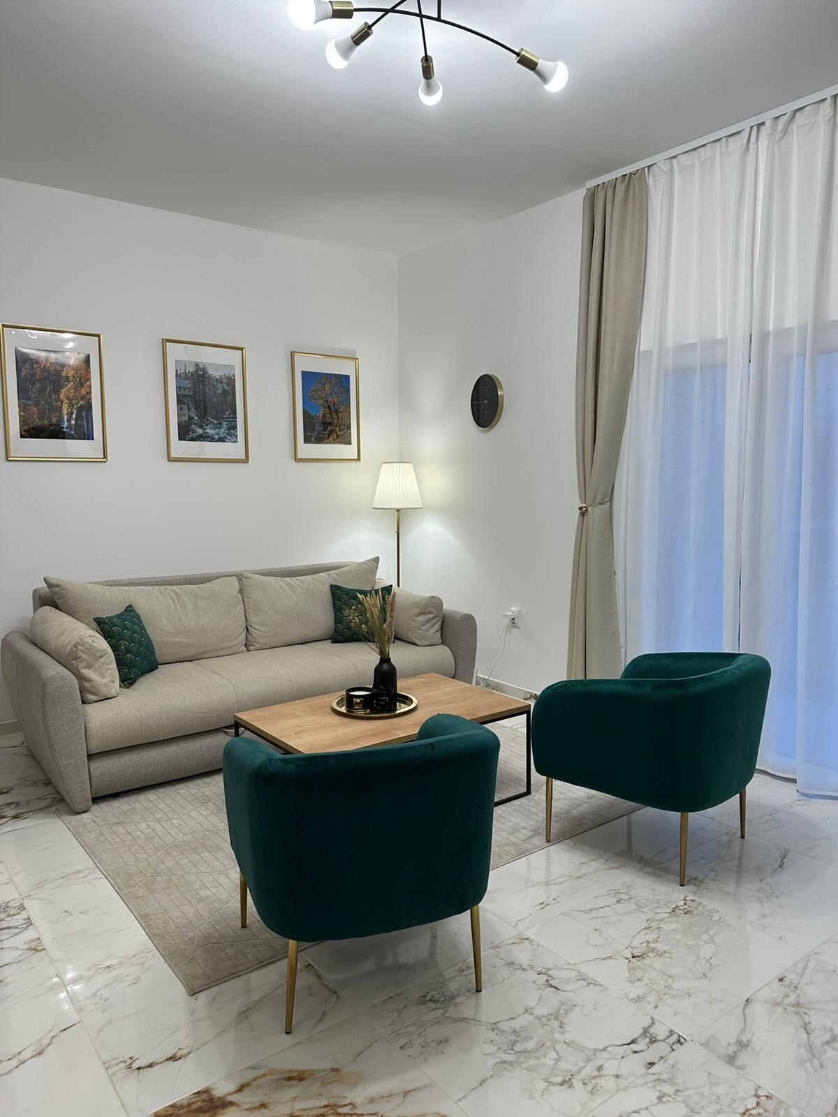 A modern living room with a sofa, two chairs, a coffee table, and framed pictures on the wall.