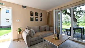 A modern living room with a sofa, a coffee table, and a sliding glass door leading to an outdoor area. - Green Linden (Rakovica)
